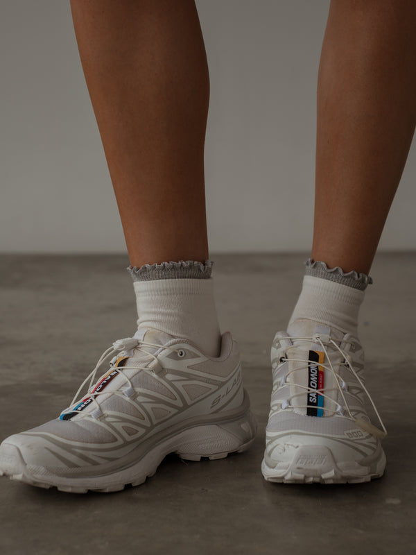 Modelo con tenis blancos y medias midi blancas con borde brillante gris.