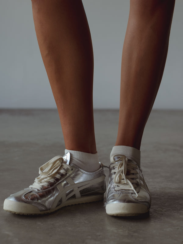 Vista frontal medias blancas tobilleras con tenis plateados. 