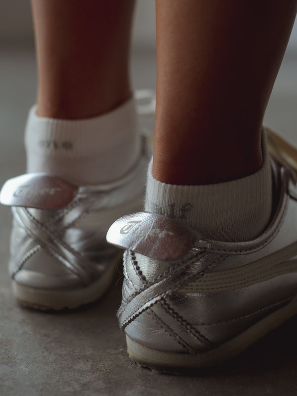 Vista a detalle bordado gris “One Half” de medias tobilleras blancas. 