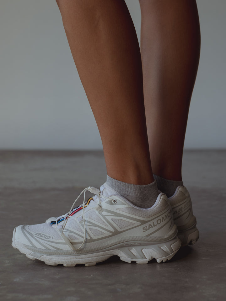 Vista lateral medias grises tobilleras con tenis blancos. 