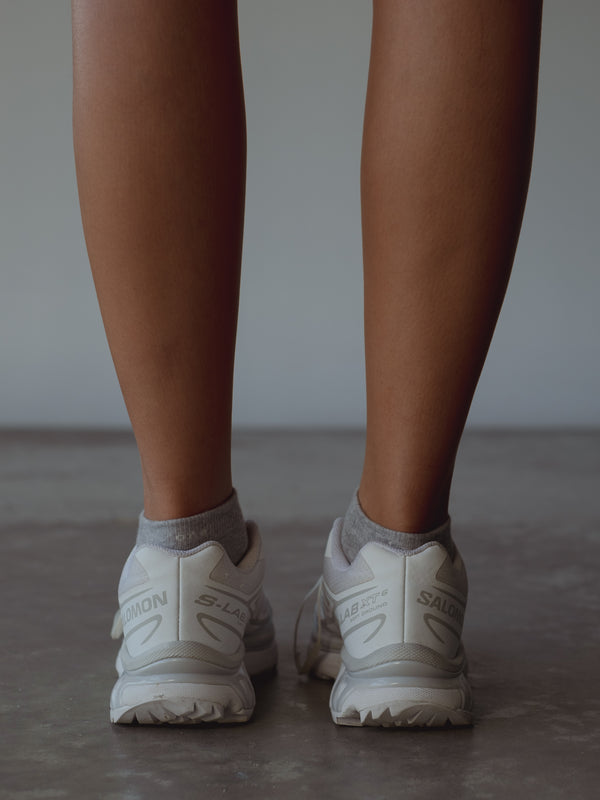 Vista posterior medias tobilleras grises con bordado blanco “One Half” en puño. 