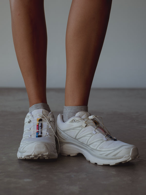 Vista frontal medias grises tobilleras con tenis blancos. 