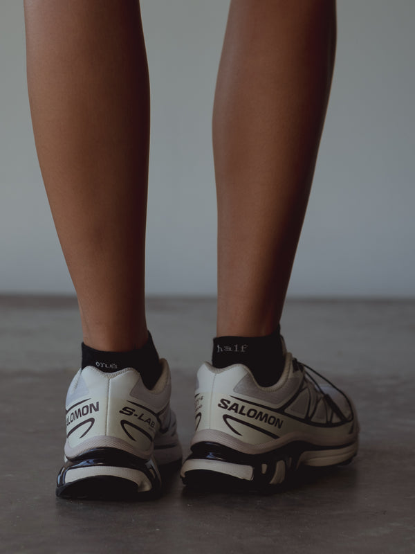 Vista posterior medias tobilleras negras con bordado blanco “One Half” en puño. 