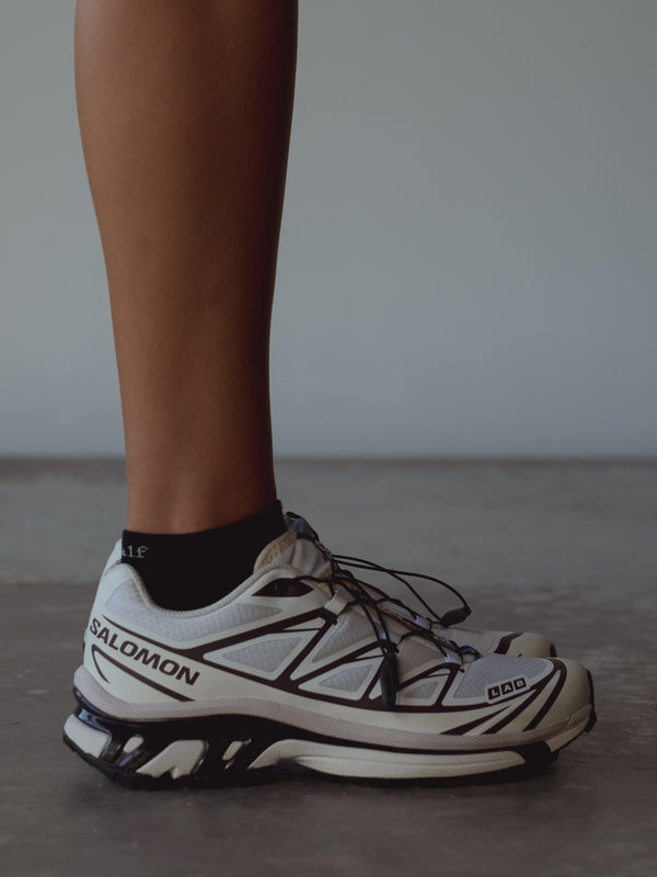 Vista lateral medias negras tobilleras con tenis blancos. 