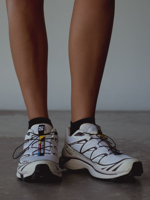 Vista frontal medias tobilleras negras con tenis blancos. 