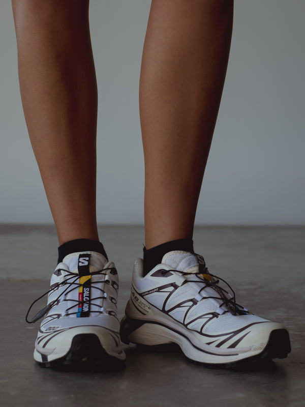 Vista frontal medias tobilleras negras con tenis blancos. 