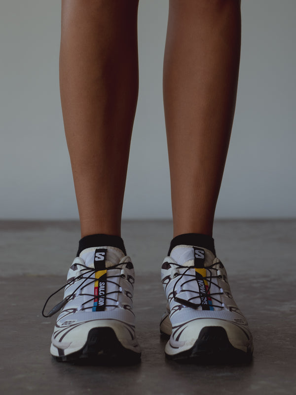 Vista frontal medias tobilleras negras con tenis deportivos.