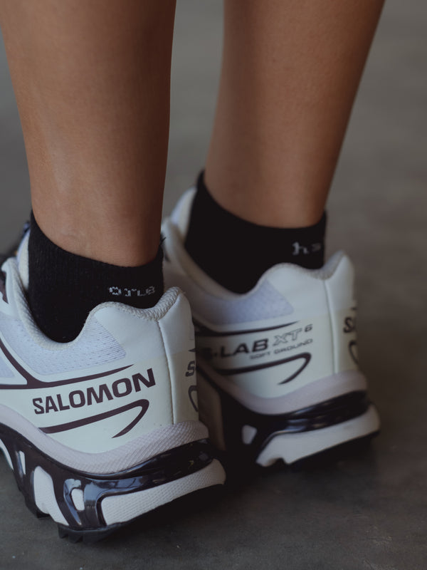 Vista a detalle bordado blanco “One Half” de medias tobilleras negras. 