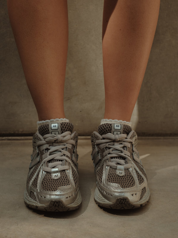 Modelo usando tenis y medias tobilleras crema de borde gris brillante.