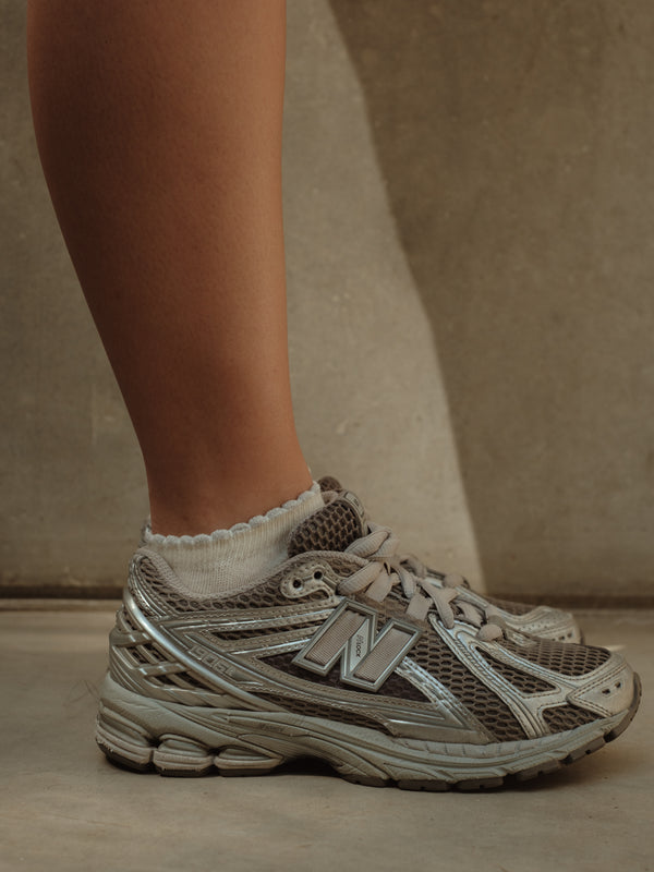 Vista lateral medias tobilleras crema de borde gris brillante con tenis.