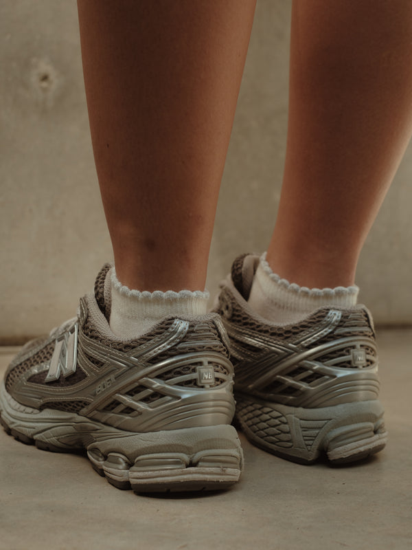 Vista posterior de medias tobilleras crema de borde brillante con tenis.