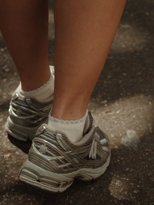 Modelo usando tenis con medias tobilleras crema de borde brillante.