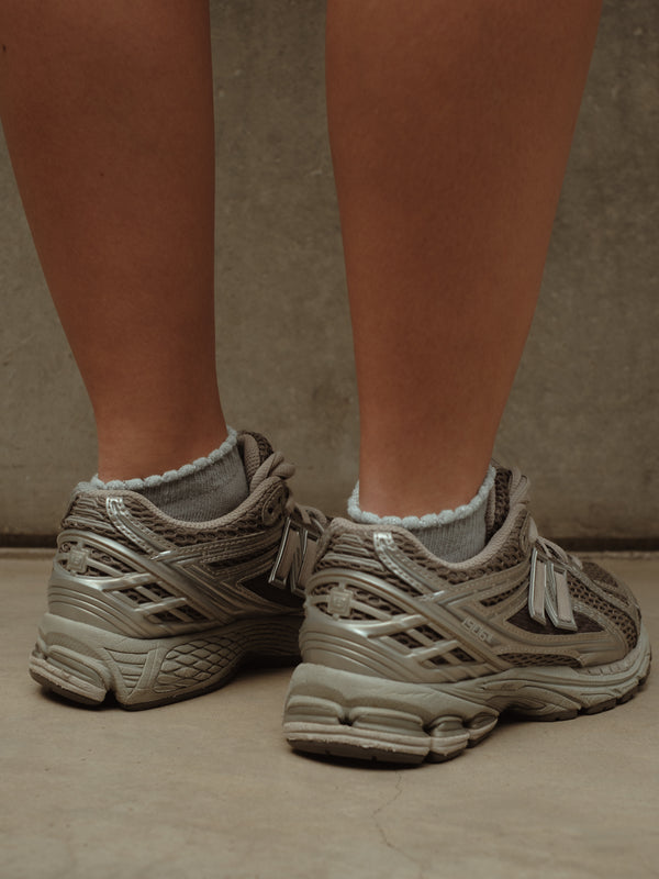 Modelo con tenis y medias tobilleras grises de borde brillante.