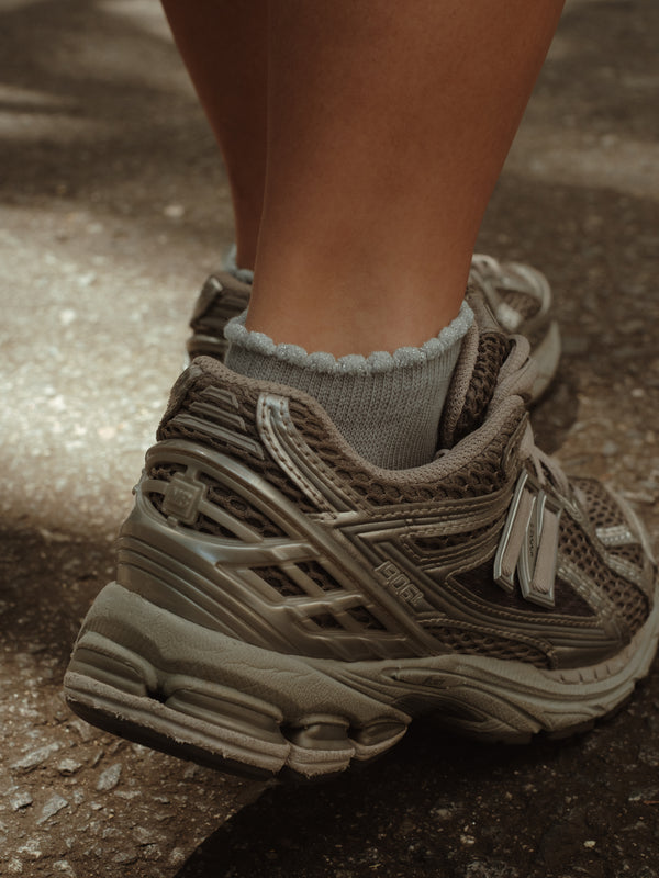 Vista posterior de tenis con medias tobilleras grises de borde brillante.