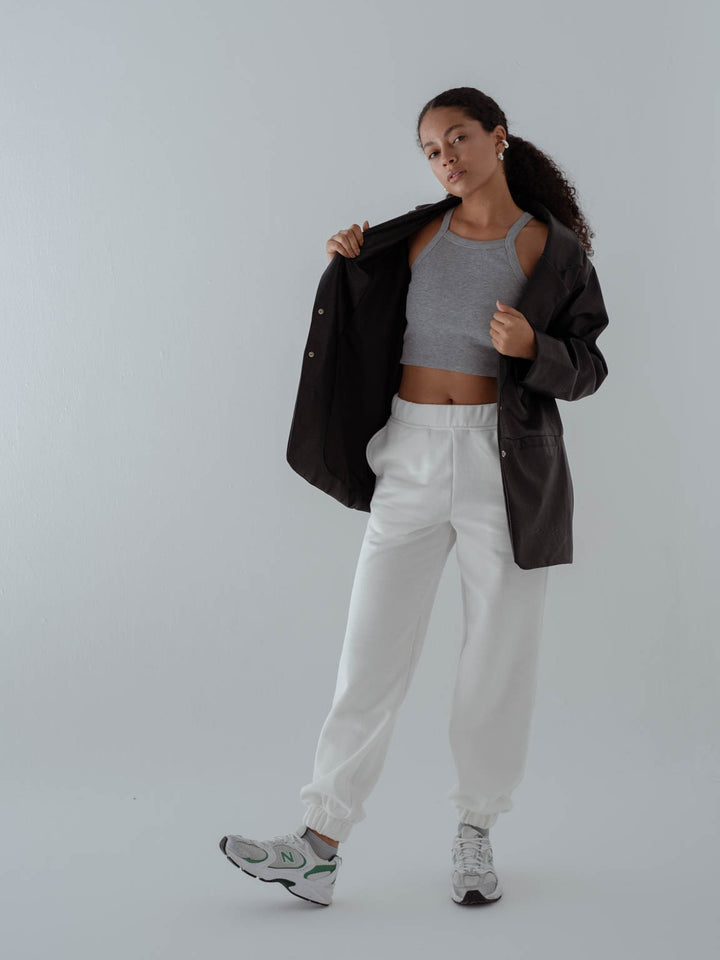 Vista completa de la modelo usando top gris, pantalón blanco, chaqueta  y medias tobilleras color gris