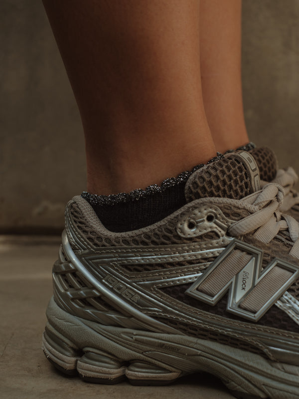 Vista lateral de tenis con medias tobilleras negras de borde brillante.