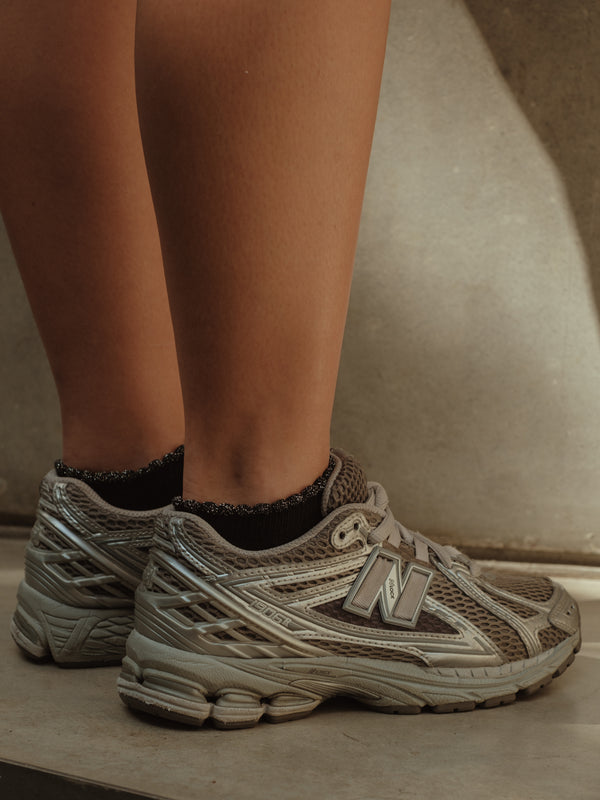 Modelo usando medias tobilleras negras de borde brillante con tenis.