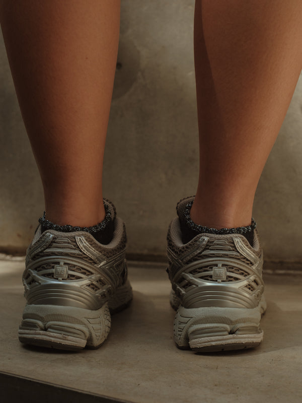 Vista posterior de tenis con medias tobilleras negras con borde brillante.