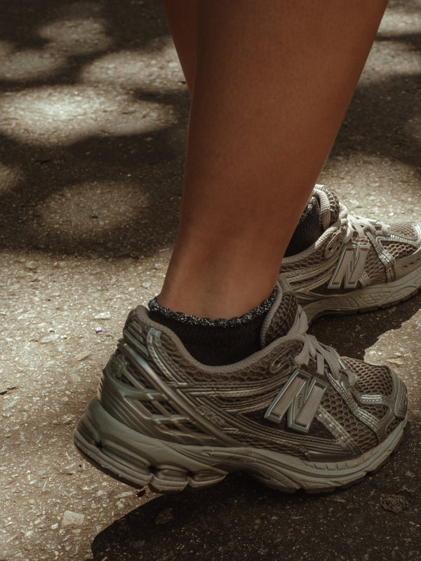 Modelo usando tenis con medias tobilleras negras de borde brillante.