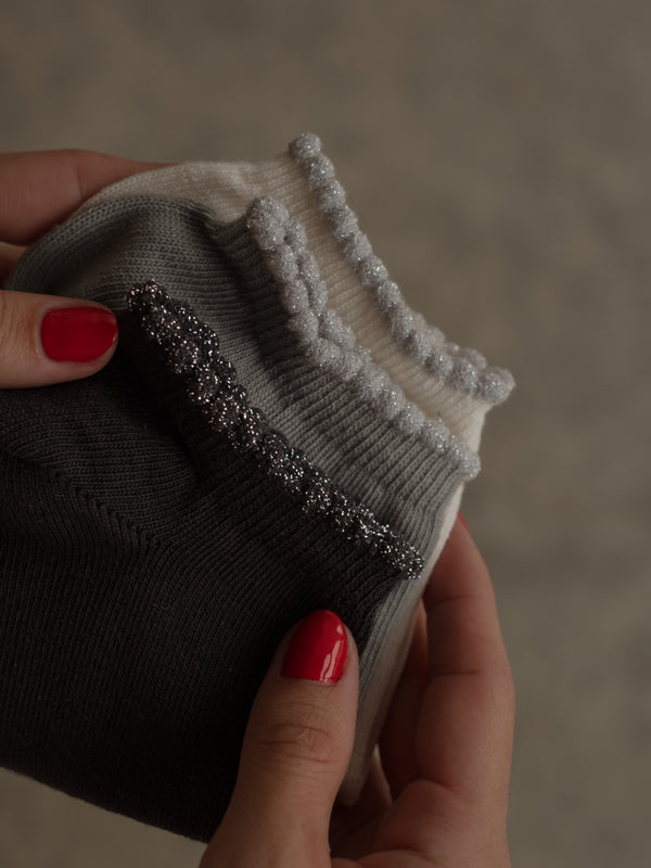 Pack x3 de medias tobilleras con borde brillante en negro, gris y crema.