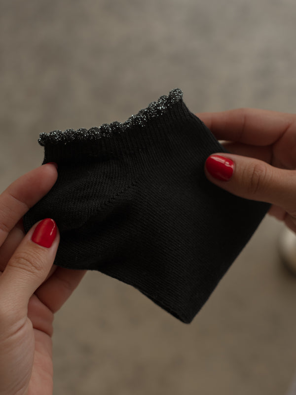 Vista frontal de medias tobilleras negras con borde brillante.