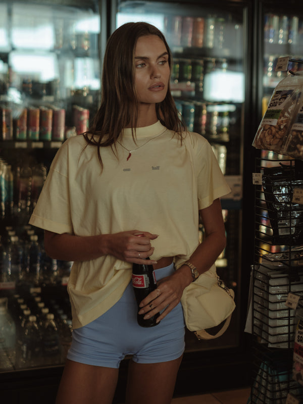 Modelo usando camiseta amarilla y mini short azul en una tienda.