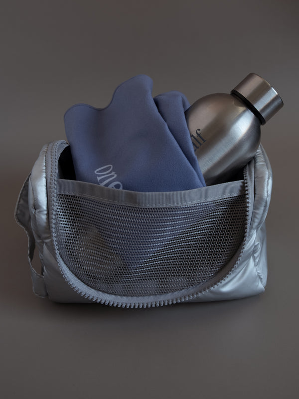 Cosmetiquera plata con termo plata y mini toalla lila dentro.