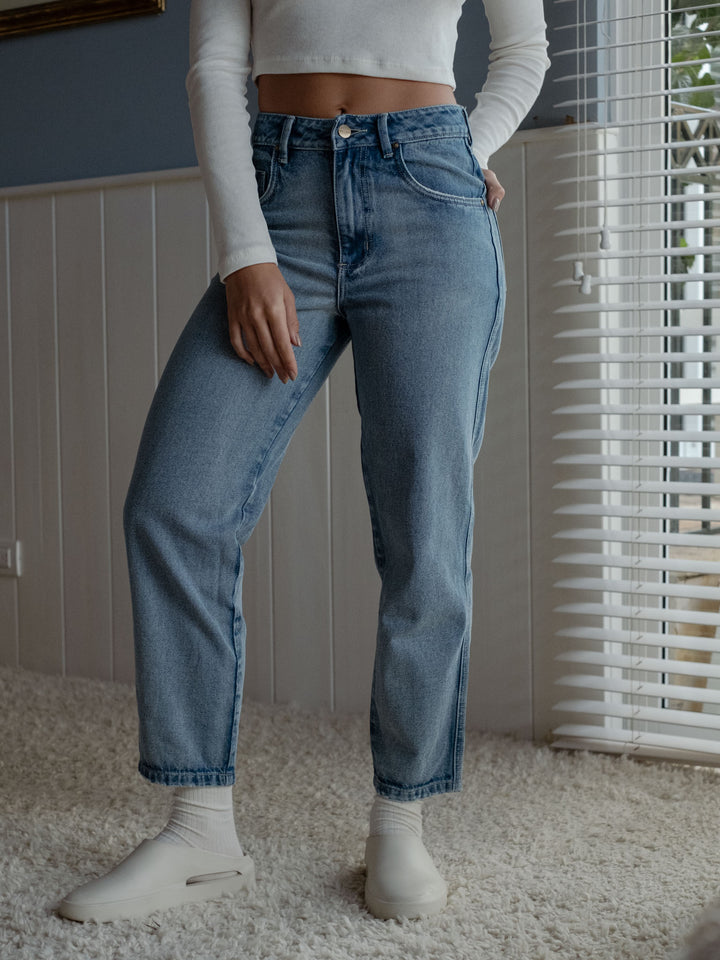 Vista inferior de la modelo usando un jean azul con ruedo al corte a la altura del tobillo