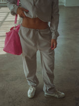 Modelo con pantalón gris claro con chaqueta del mismo tono y bolso fucsia. 
