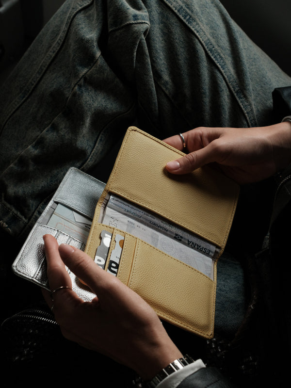 Modelo sosteniendo dos porta pasaporte abiertos.