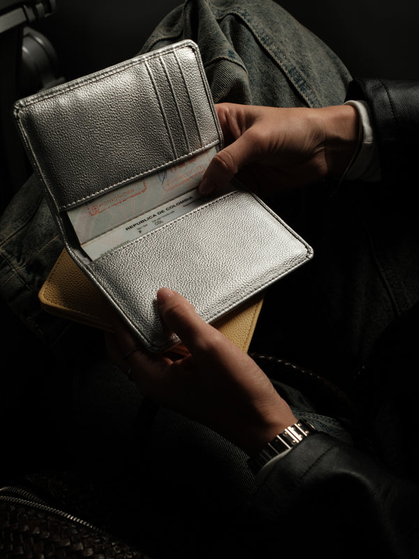 Modelo con porta pasaporte plata abierto en la mano.