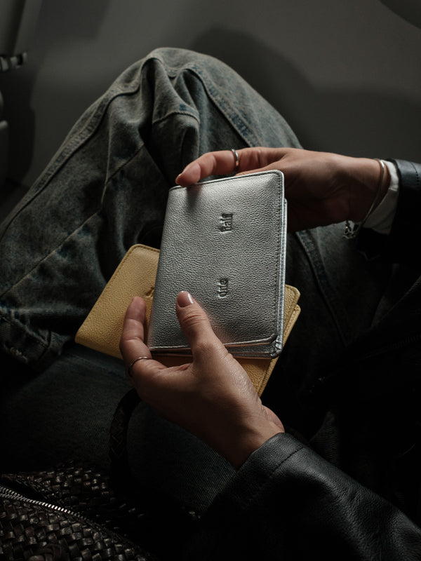 Modelo con porta pasaporte plata en las manos.