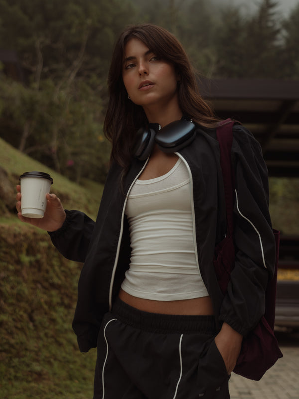 Modelo usando chaqueta negra rompevientos con top crudo.