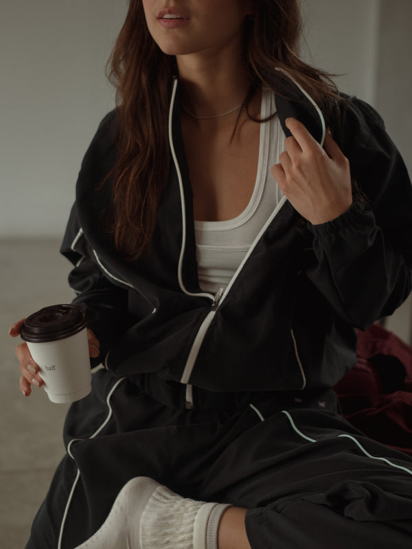 Modelo con chaqueta negra con líneas crudo con top y pantalón. 