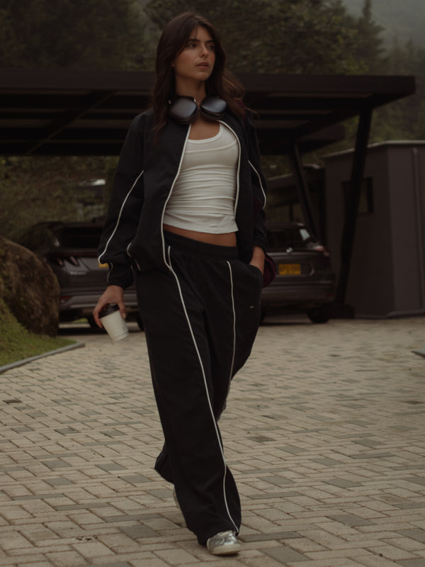 Modelo usando set de chaqueta y pantalón negro con top crudo.