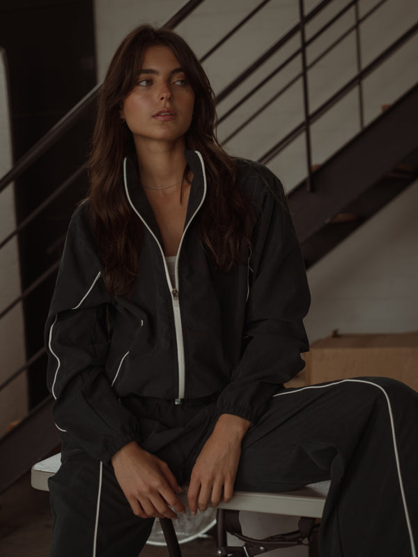 Modelo con set de chaqueta y pantalón negro con líneas en crudo.