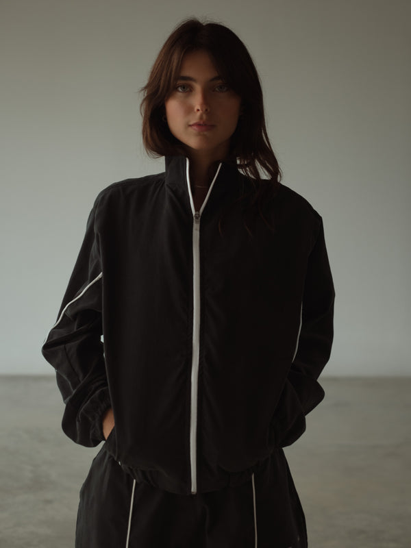 Vista frontal modelo usando chaqueta negra rompevientos.