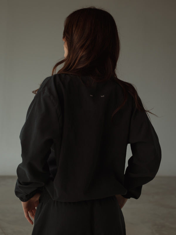 Vista posterior chaqueta negra con estampado "One Half" pequeño.