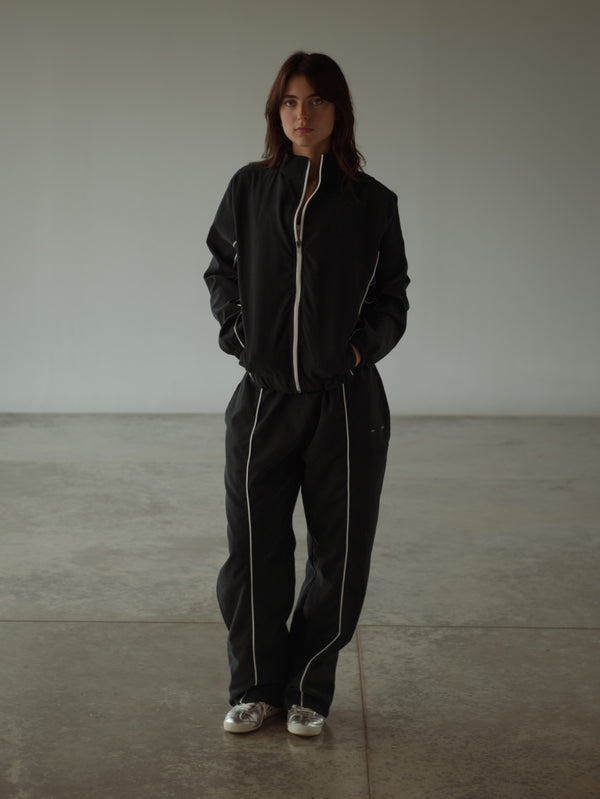 Vista frontal modelo con set de ropa para mujer, chaqueta y pantalón negro.