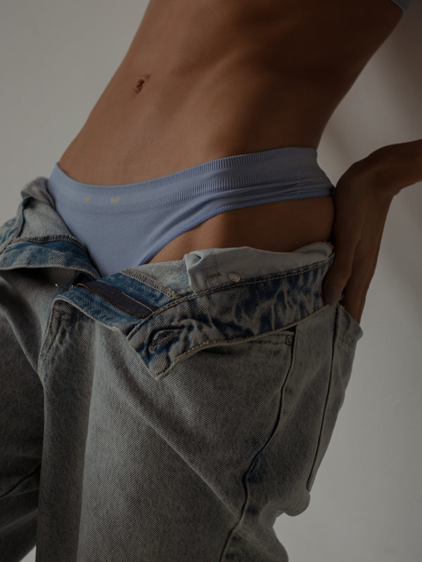 Vista a detalle de pretina de tanga azul sin costuras con jean clásico. 