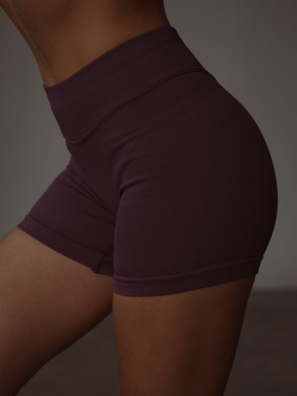 Vista lateral short deportivo vino pretina curva en poliamida.