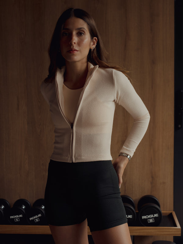 Modelo con top y chaqueta crema con short deportivo negro.