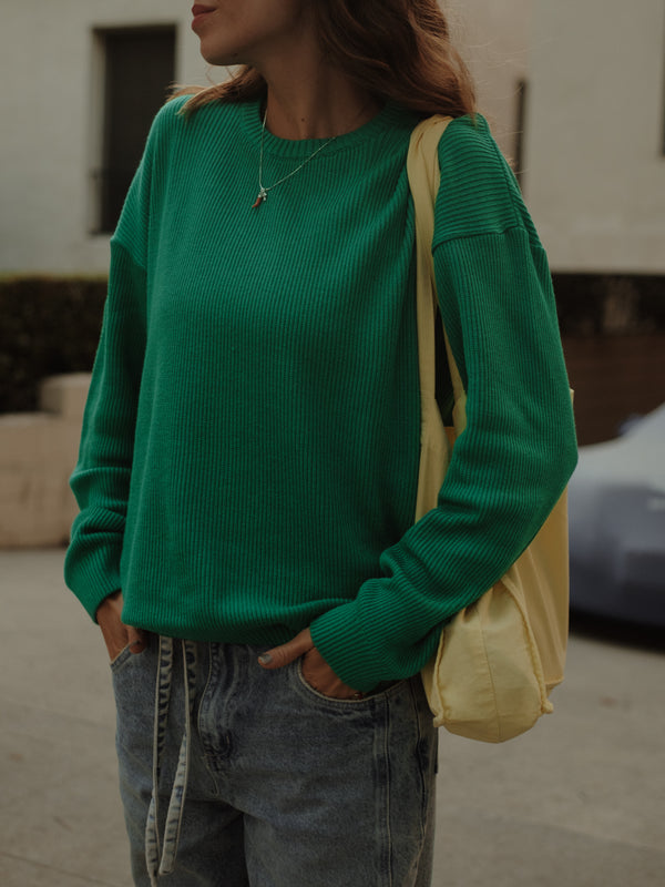 Vista frontal de suéter tejido verde con jean azul y tote bag amarilla.