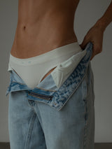 Modelo usando tanga crudo con jean azul claro.