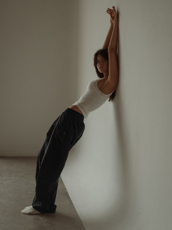 Modelo usando pantalón negro con crop top crema doble de tiras.