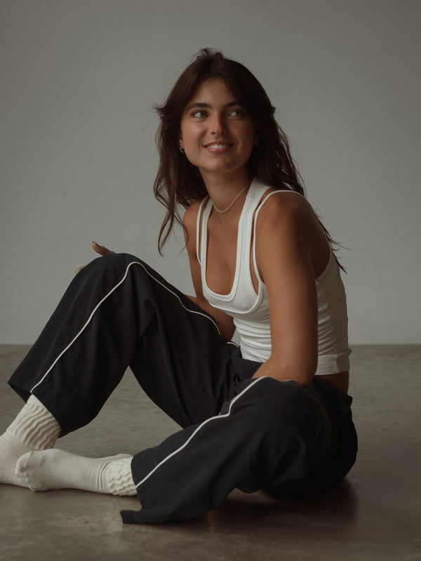 Modelo sentada usando crop top color crema doble con pantalón negro.