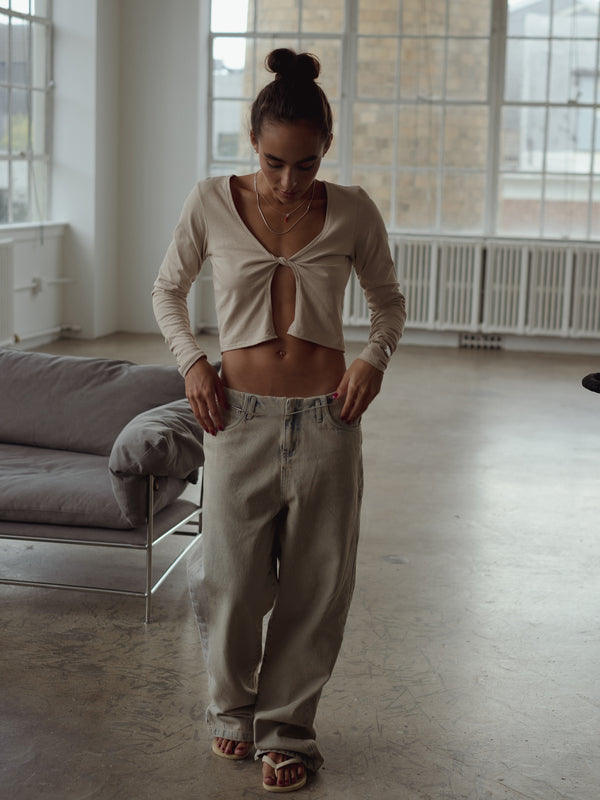 Modelo de frente usando jean ancho, sandalias y top de nudo taupe.