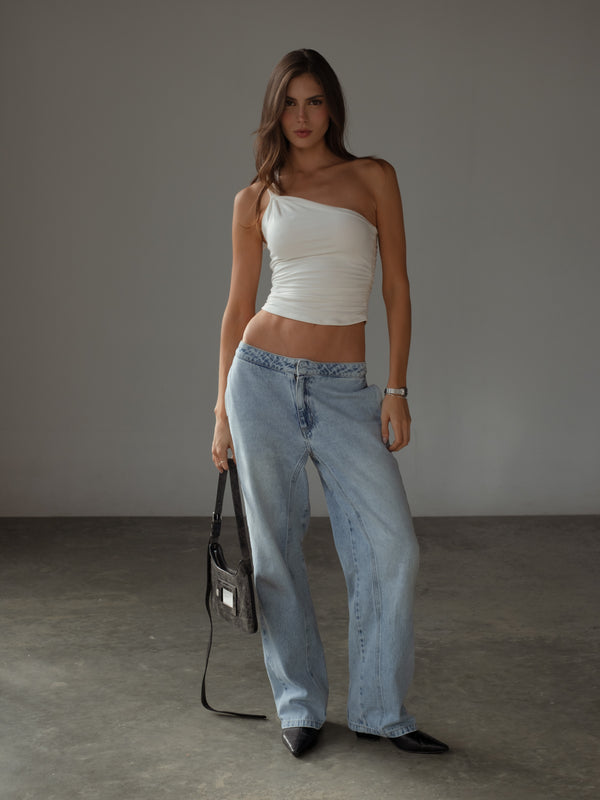 Modelo usando jean tiro bajo azul con crop top ajustado crudo.