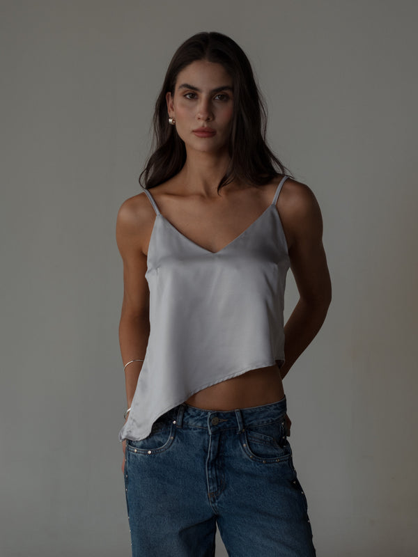 Modelo usando top de tiras plata ruedo diagonal con jean.