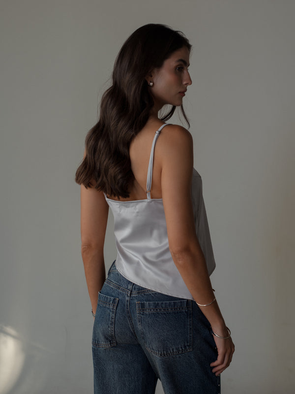Modelo de espalda usando top de tiras satinado plata con jean azul.